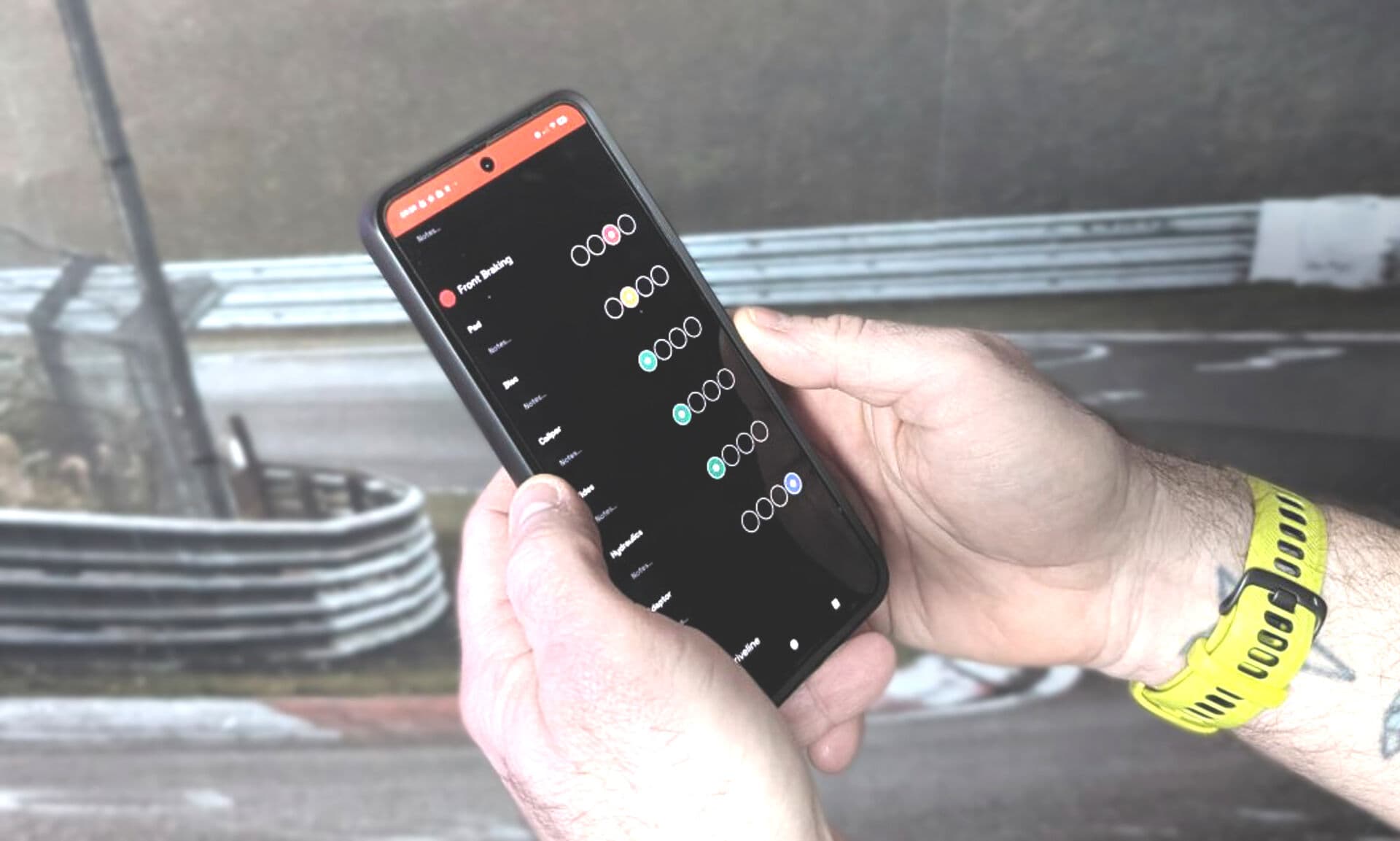 A driver holding a phone at the circuit