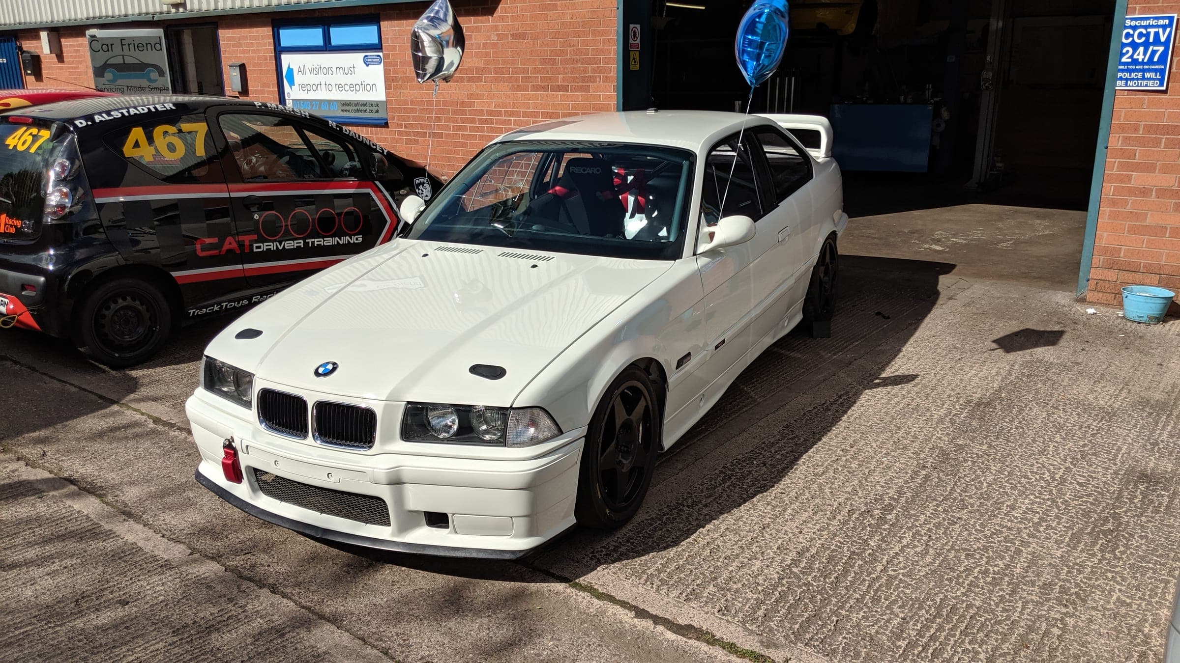 A white BMW E36 track car outside the TTR Motorsport workshop