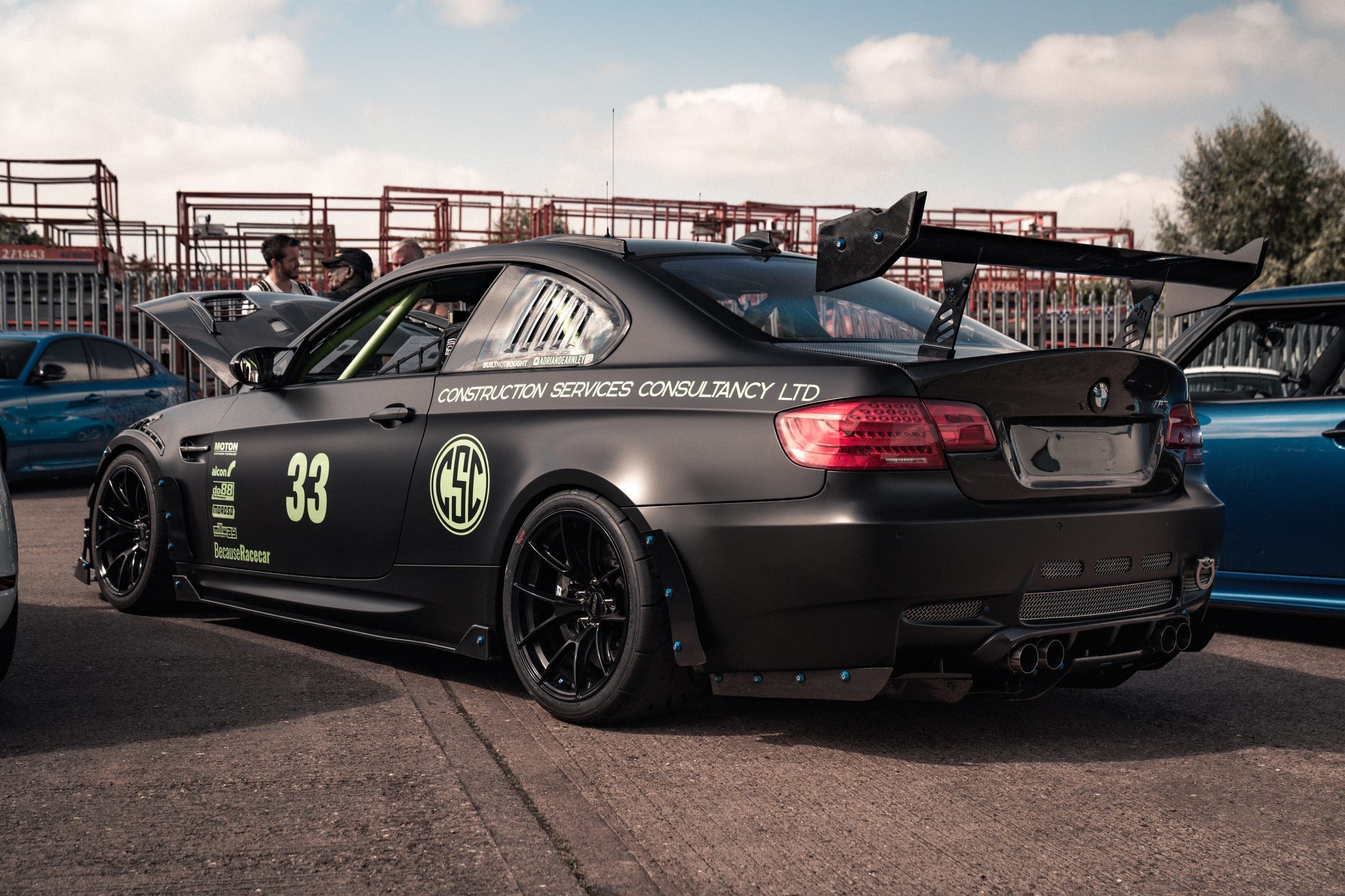 A black BMW M3 race car in the paddock