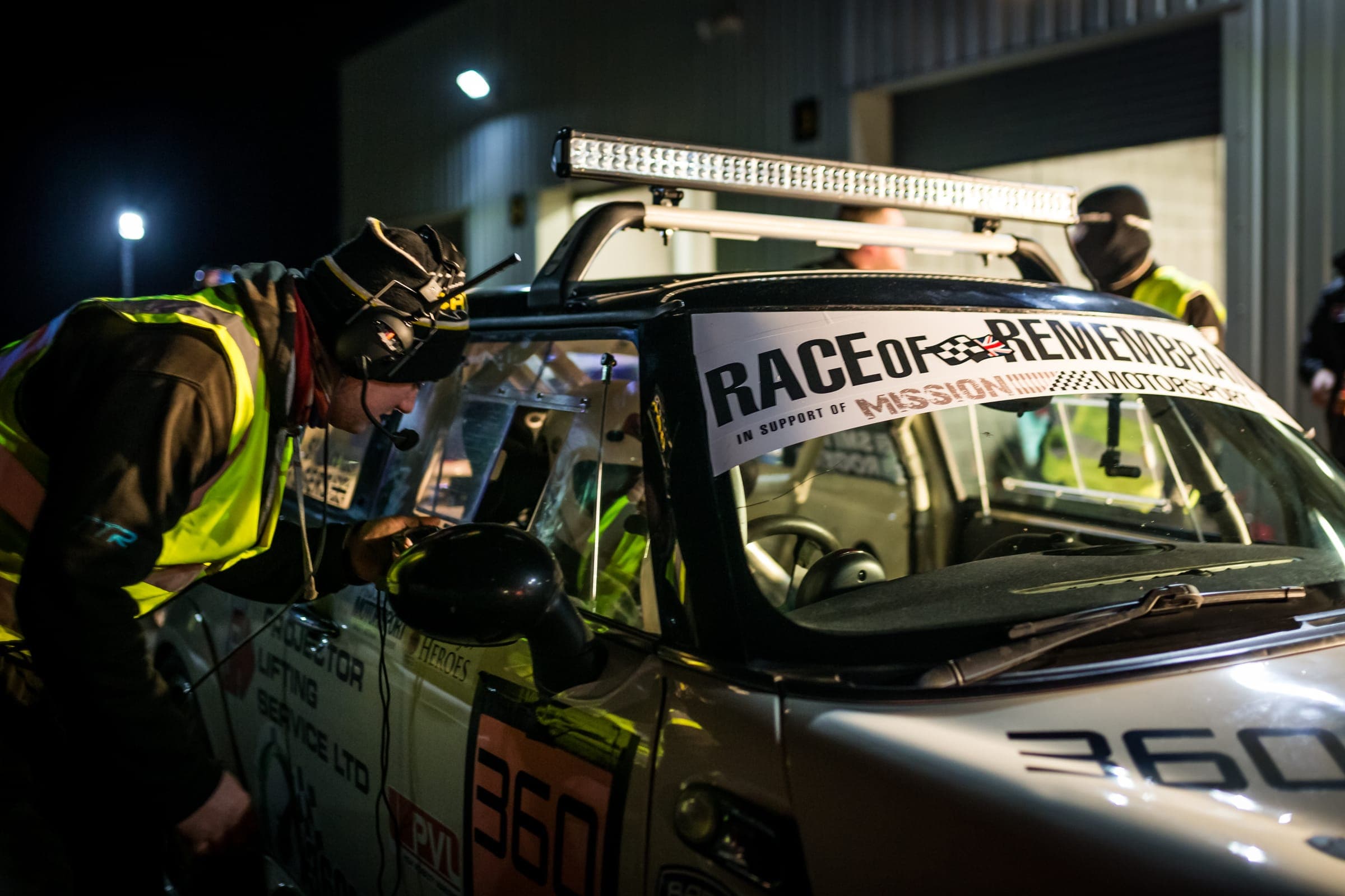A crew at work on a race car at night at the Race of Remembrance
