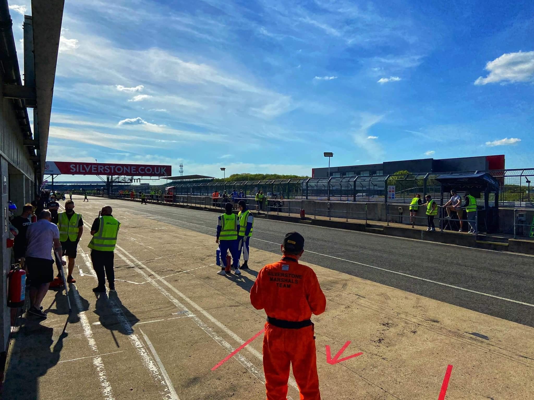 Drivers and crew in the pit lane at Silverstone on a sunny day