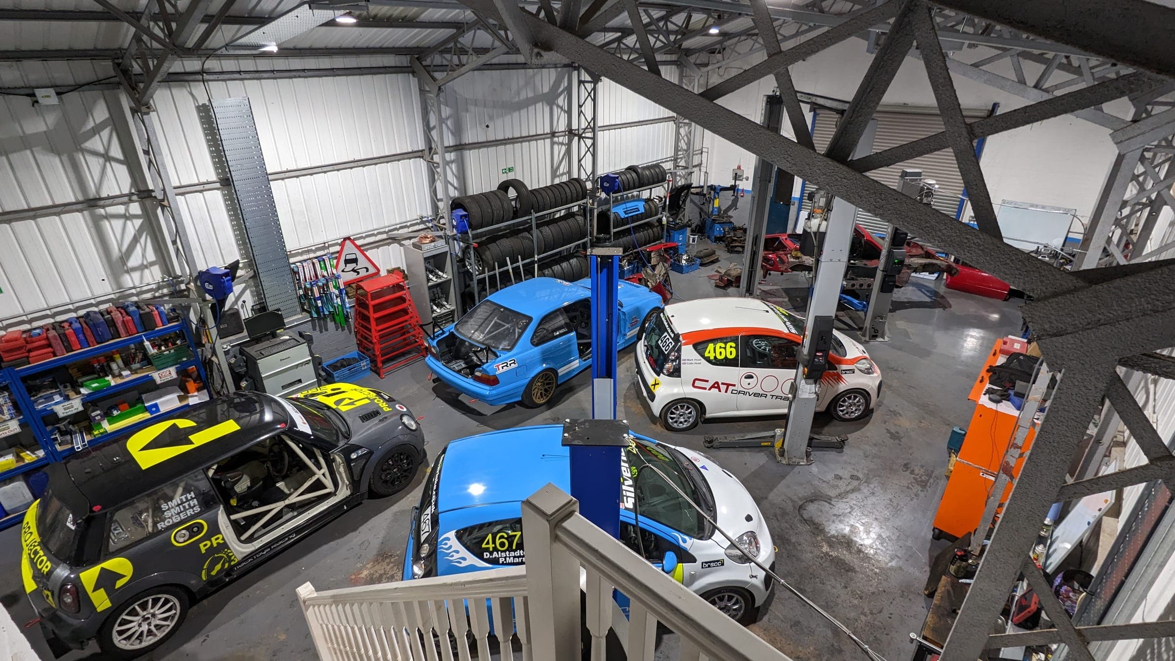 Race cars being worked on, seen from the workshop stairs